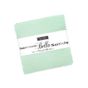 May include: A stack of square, light green fabric squares, held together by a white band. The band features the text "Elizabeth's Favorites Bella Solids by moda". The fabric has a textured appearance.