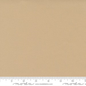 May include: A solid beige fabric with a subtle texture. The fabric is measured in inches with the text "moda" printed on the ruler.