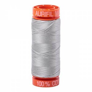 May include: A spool of silver gray thread with an orange label that reads "Aurifil 100% Cotton".