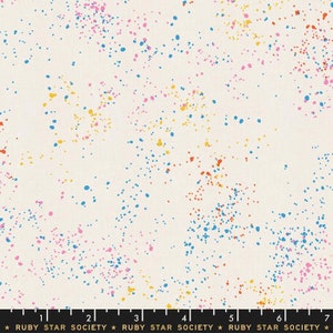 May include: A white fabric with a speckled pattern of blue, pink, yellow, and orange dots. The fabric is marked with a ruler in inches and the text "RUBY STAR SOCIETY".