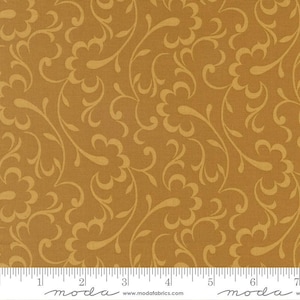 May include: Mustard-colored fabric with a repeating floral and vine pattern. The design features stylized flowers and flowing lines in a lighter shade of gold. The fabric has a textured appearance and is suitable for various sewing projects.