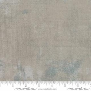 May include: A close-up of a light gray fabric with a subtle blue and white pattern. The fabric has a textured, slightly distressed look.