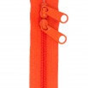 May include: Orange zipper with two sliders. The zipper is closed and has a smooth finish.