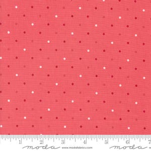 May include: A coral pink fabric with a white polka dot pattern. The fabric is shown with a ruler for scale.