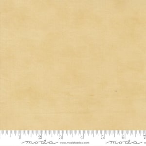 May include: A close-up of a piece of fabric in a light tan color. The fabric has a subtle texture and a ruler is at the bottom of the image. The fabric is likely used for quilting or other sewing projects.