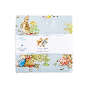 May include: A stack of fabric squares featuring illustrations of Peter Rabbit and Benjamin Bunny on a light blue background. The fabric has a repeating pattern of the characters and garden elements. The fabric is wrapped with a white band that has the Riley Blake Designs logo and the Peter Rabbit and Benjamin Bunny text.