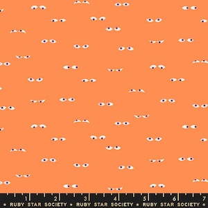 May include: A peach-colored fabric with a repeating pattern of white eyes. The eyes are of various sizes and some are closed. The fabric has a black and white ruler with the text "RUBY STAR SOCIETY" printed on it.