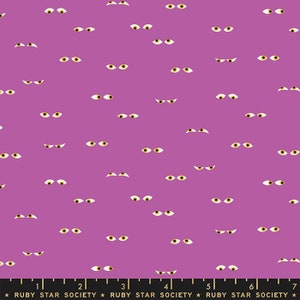 May include: Purple fabric with a repeating pattern of white eyes with yellow pupils. The fabric has a ruler printed at the bottom with the text "Ruby Star Society".