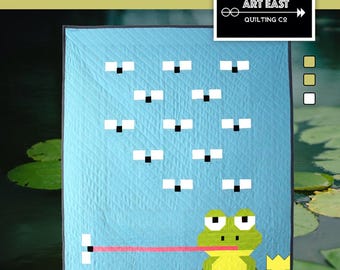 May include: A quilt pattern featuring a frog with a crown and a tongue sticking out, surrounded by lily pads and a blue background with white squares. The pattern is titled "Welcome to My Pad" and is 42 inches by 53 inches.