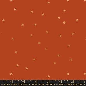 May include: A rust-colored fabric with a repeating pattern of small gold stars.