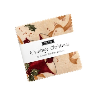 May include: A beige fabric square with a red, white, and green design featuring a bell and holly. The fabric has the text "A Vintage Christmas by Kansas Troubles Quilters" printed on a white label.