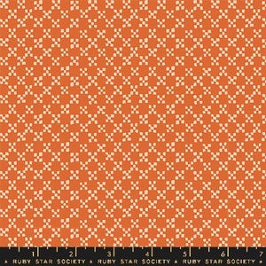 May include: Orange fabric with a repeating pattern of small, off-white cross-like shapes. The fabric has a warm, autumnal color palette. The bottom of the image includes a ruler with the text "RUBY STAR SOCIETY".