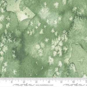 May include: Green watercolor fabric with a white speckled pattern. The fabric has a subtle, faded look, like a vintage watercolor painting. The fabric is perfect for quilting, crafts, and home decor.