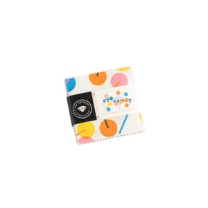 May include: A white fabric square with a colorful eye candy design. The fabric features a repeating pattern of circles and lines in pink, orange, yellow, and blue. The fabric is labeled "eye candy" and "Charm Pack Collection" in black text.