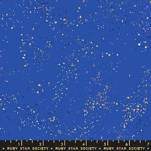 May include: A blue fabric with a speckled pattern of gold, purple, and green dots. The fabric is from Ruby Star Society.