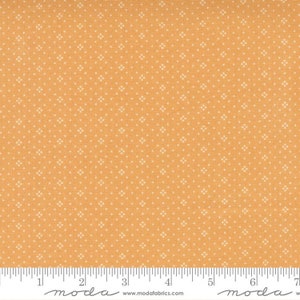 May include: A close-up of a fabric with a small white diamond pattern on a light orange background. The fabric is measured with a ruler in inches.