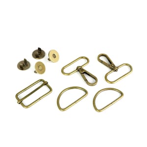 May include: Assortment of gold-toned metal hardware for bags and purses, including D-rings, swivel clasps, and magnetic closures.