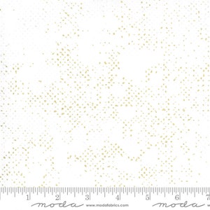 May include: White fabric with a subtle gold speckled pattern. The fabric is marked with a ruler and the words "moda" and "www.modafabrics.com".