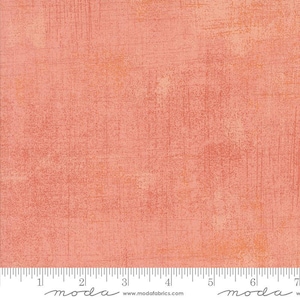 May include: A close-up of a textured fabric with a mottled, painterly effect. The fabric is primarily a warm coral color, with lighter peach and orange tones. Vertical and horizontal brushstroke-like marks add visual interest. The fabric is likely used for quilting or crafting.