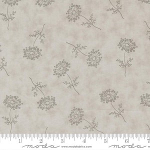 May include: A beige fabric with a repeating pattern of delicate gray floral sprigs. The fabric has a subtle textured appearance and includes a ruler with the word "moda" printed on it.