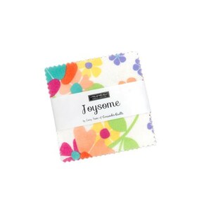May include: A square stack of fabric squares featuring a white background with a colorful floral pattern in shades of pink, orange, yellow, green, and purple. A white paper band wraps around the center with the text Joysome by Corey Yoder of Coriander Quilts.