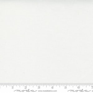 May include: A plain white fabric with a subtle texture. The fabric is measured with a ruler that has the word "moda" printed on it.
