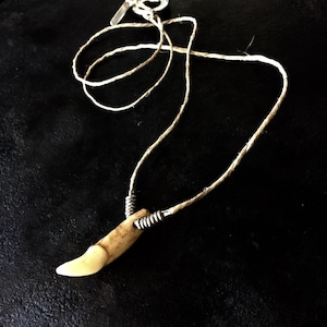 Wolftandketting aan een hennepkoord, wolventandketting, lichtgekleurde wolventand aan een hennepketting, wolventandketting met zilveren ringen