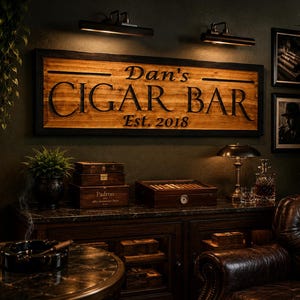 May include: A dimly lit cigar bar with a wooden sign that reads "Dan's Cigar Bar Est. 2018". The room features a leather armchair, a table with a cigar and ashtray, and a cabinet with cigar boxes.