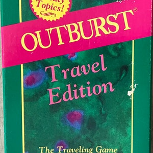 May include: A green box with a yellow and pink label that says "OUTBURST Travel Edition". The label also says "The Traveling Game of Verbal Explosions". There is a yellow star on the box that says "All Family Topics!"