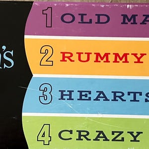May include: A colorful box set of four children's card games. The box features the text "4 Children's Card Games" with the games listed as Old Maid, Rummy, Hearts, and Crazy Eights. The box is designed for ages 4 and up.