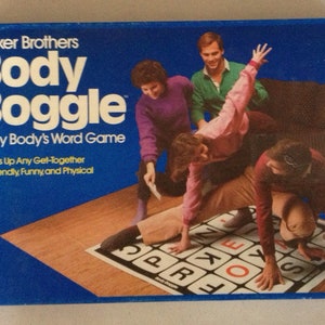 May include: A blue game box with the title "Body Boggle" and the tagline "Every Body's Word Game". The box shows four people playing the game, which involves using their bodies to spell words on a game board.