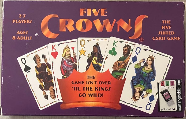 Puede incluir: Una caja del juego de cartas Five Crowns con un fondo morado y el t&iacute;tulo del juego en naranja. La caja presenta naipes con reyes y reinas. El texto en la caja incluye "2-7 jugadores" y "Edades 8-Adultos."