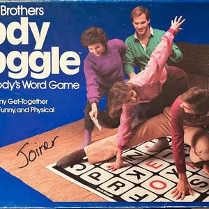 May include: A vintage Parker Brothers Body Boggle board game box with the game in play. The box is blue with white and yellow text. The game involves people spelling words with their bodies on a grid.