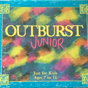 May include: A teal-colored board game box with the title "OUTBURST JUNIOR" in yellow and pink lettering. The background features a colorful abstract design. The box also includes the text "Just for Kids Ages 7 to 14".