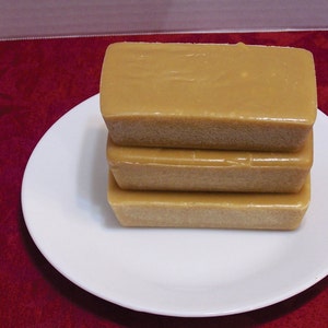 Puede incluir: Tres bloques rectangulares de fudge marr&oacute;n claro apilados en un plato blanco. El fudge es liso y brillante.