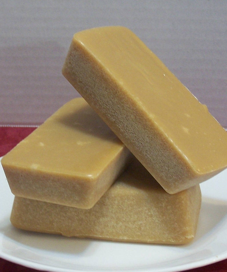 Puede incluir: Tres barras rectangulares de caramelo marr&oacute;n claro apiladas en un plato blanco.