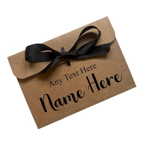 May include: A brown paper envelope tied with a black satin ribbon bow. The text "Any Text Here" and "Name Here" are printed in black cursive font on the front of the envelope.