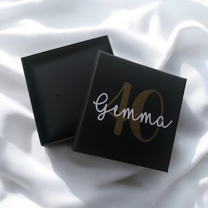 May include: Black gift box with a gold number 40 and the name "Gemma" written in white script.