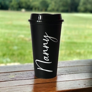 Könnte beinhalten: Schwarze Reisebecher mit einer weißen Aufschrift "Manny".
