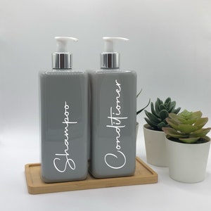 May include: Two gray pump bottles with white labels. The bottle on the left says "Shampoo" and the bottle on the right says "Conditioner".