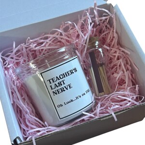 Peut inclure: Une bougie blanche dans un pot en verre avec une étiquette indiquant "TEACHER'S LAST NERVE Oh Look...It's on FIRE" et un petit flacon d'allumettes, le tout dans une boîte en carton blanc remplie de papier déchiqueté rose clair.