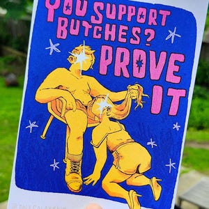 Puede incluir: Una ilustraci&oacute;n azul y amarilla de dos figuras con el texto "YOU SUPPORT BUTCHES? PROVE IT" en rosa. La ilustraci&oacute;n est&aacute; sobre un fondo azul con estrellas blancas.