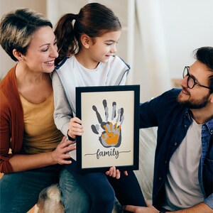 May include: A framed print featuring a handprint design in grey and orange. The print reads "family" at the bottom.