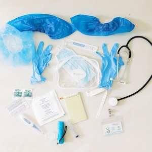 May include: A medical kit containing a black stethoscope, blue nitrile gloves, blue shoe covers, a light blue bouffant cap, a clear plastic pouch, a yellow notepad, a blue flashlight, a white wristband, a syringe, and various small medical packets.