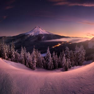 May include: A panoramic view of a snow-covered mountain range at sunset. The sky is a vibrant mix of pink, purple, and orange, with a few stars visible. The mountain peaks are covered in snow, and the trees in the foreground are also covered in snow.