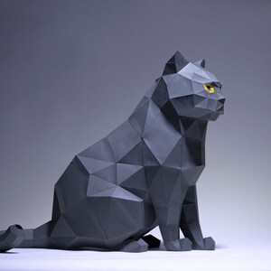Pode incluir: Uma escultura de gato de origami cinza com olhos amarelos. O gato est&aacute; sentado com o rabo enrolado atr&aacute;s dele.