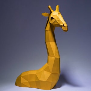 Op de afbeelding: Een gele papieren giraffesculptuur met een geometrisch ontwerp. De giraffe zit met zijn hoofd naar de zijkant gedraaid.