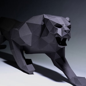 May include: A black papercraft sculpture of a panther in a crouching position. The panther is made of folded paper and has a realistic appearance.