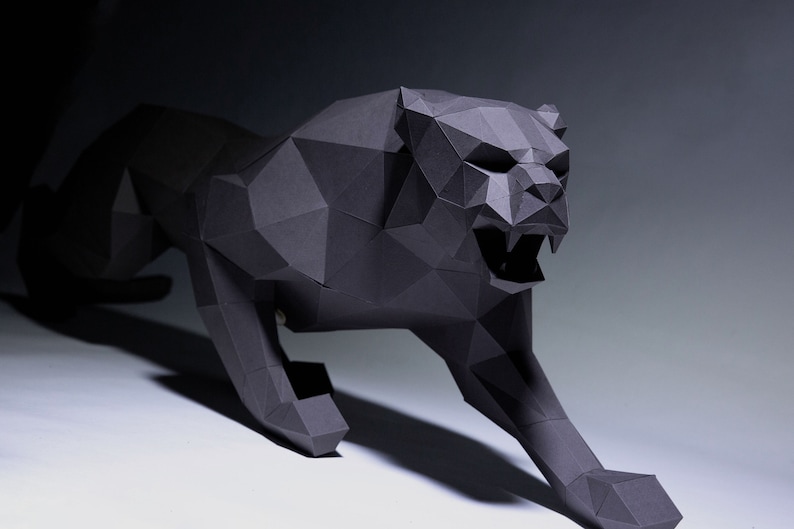 May include: A black papercraft sculpture of a panther in a crouching position. The panther is made of folded paper and has a realistic appearance.