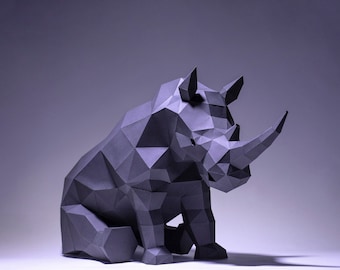 Pode incluir: Uma escultura de rinoceronte de origami cinza com um design geométrico. A escultura está sentada em uma superfície branca.